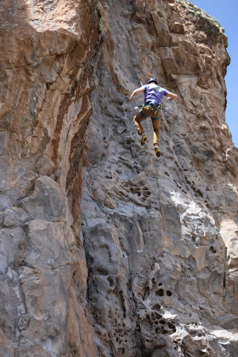 Climber girl holding on volcanic stone texture during climbing tour offered by Climbing rooftop and PeruClimb in Colca Canyon Coporaque Peru